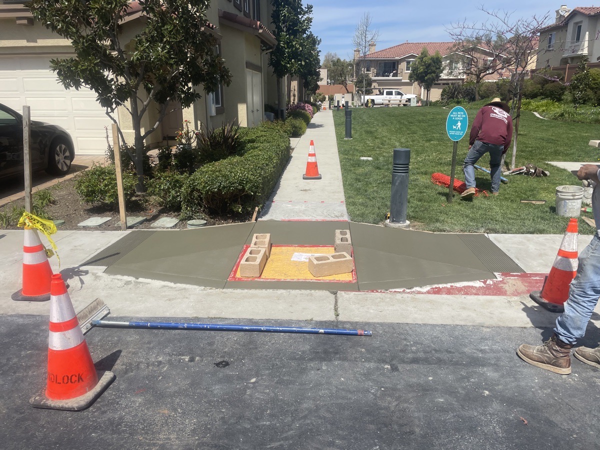 Second fresh concrete walkway transition beside an existing landscaped path